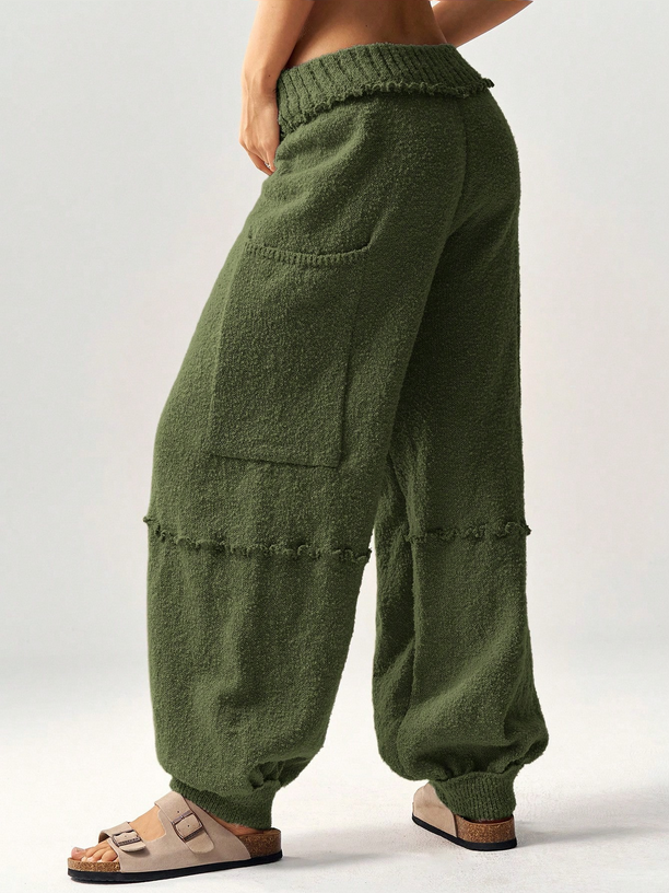 Green knitted pants worn by a person on a white background