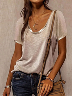 Person wearing a light gray t-shirt and blue jeans, holding a brown handbag against a neutral background.