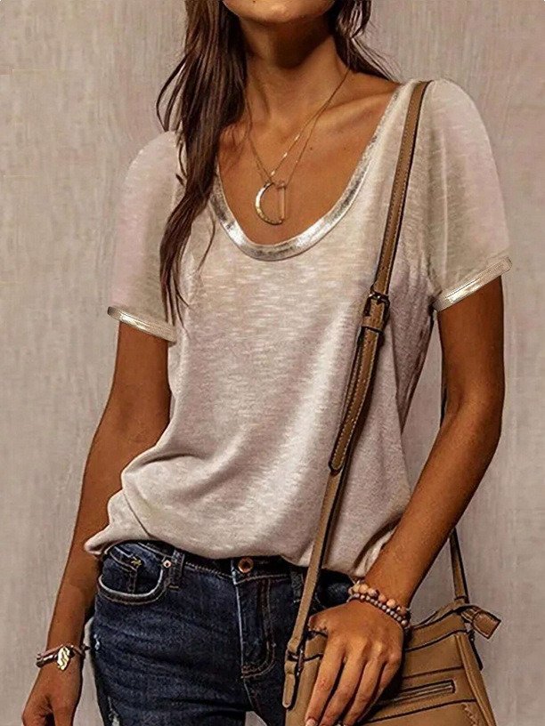 Person wearing a light gray t-shirt and blue jeans, holding a brown handbag against a neutral background.