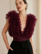 Woman wearing a burgundy ruffled top against a neutral background