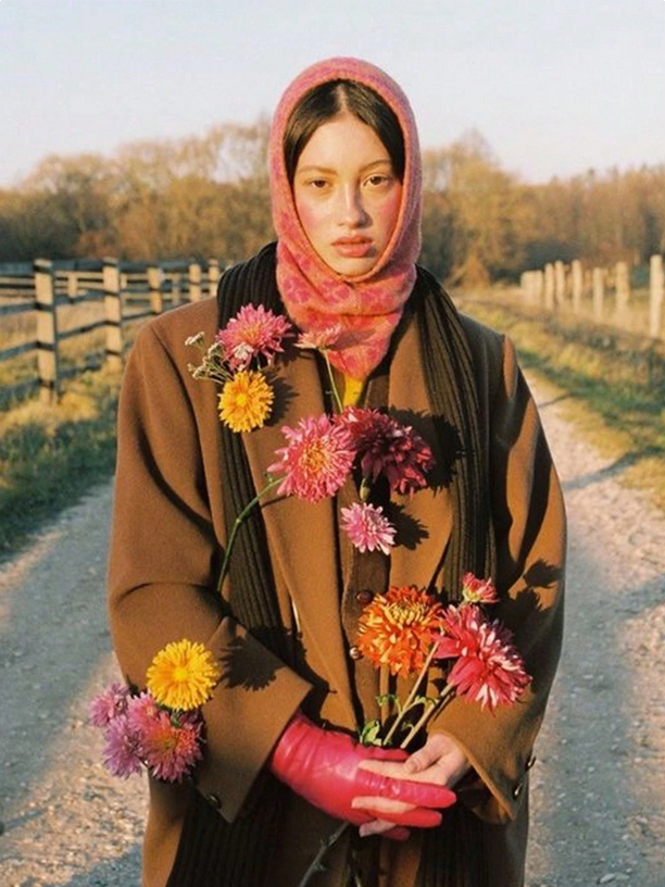 Person holding flowers on a rural road