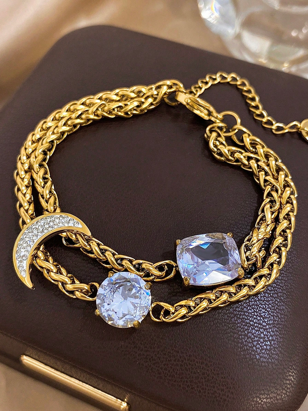 Gold chain bracelet with crystal stones on a dark surface