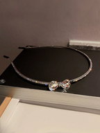 Silver choker necklace with a bow-shaped crystal pendant on a black surface.