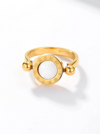 Gold ring with a circular design and ball accents on a white background