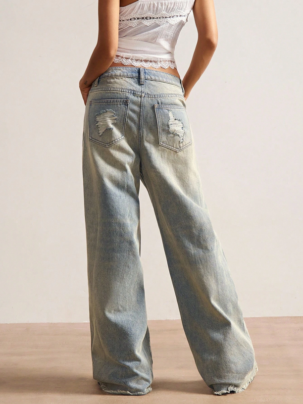 Person wearing light blue jeans with a plain background