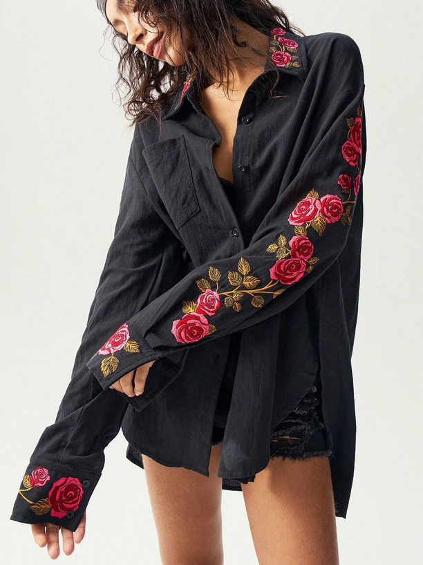 Black shirt with red floral embroidery on a plain background
