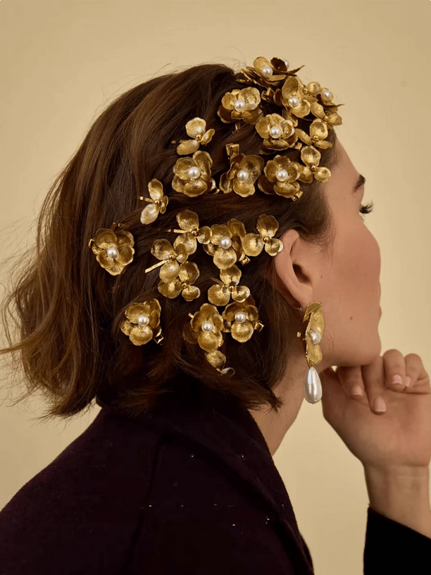 Woman wearing a gold floral headpiece and matching earrings against a beige background