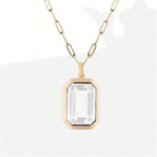 Gold necklace with a clear gemstone pendant on a white background