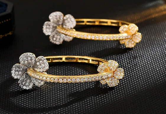 Two gold and silver flower-shaped bangles on a dark textured surface