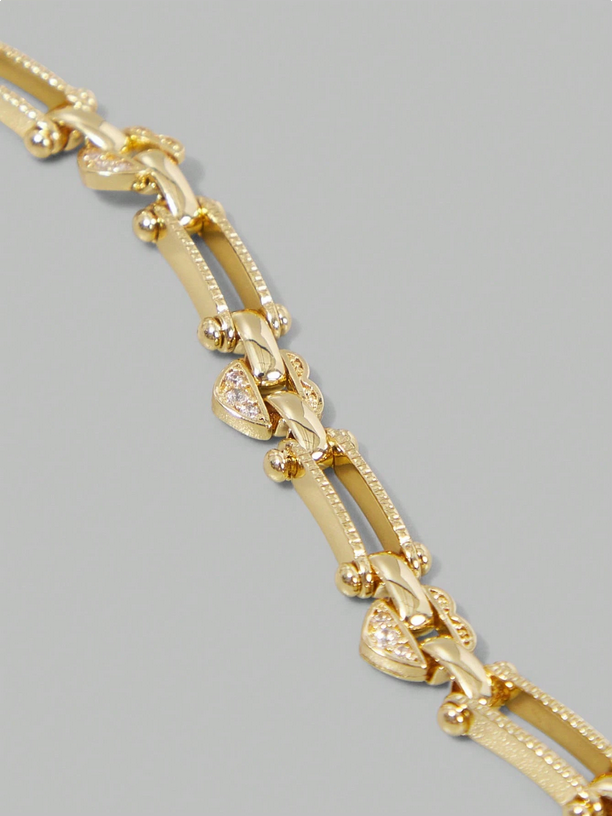 Gold bracelet with heart-shaped charms on a gray background