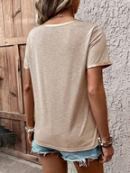 Person wearing a beige t-shirt and denim shorts against a textured wall.