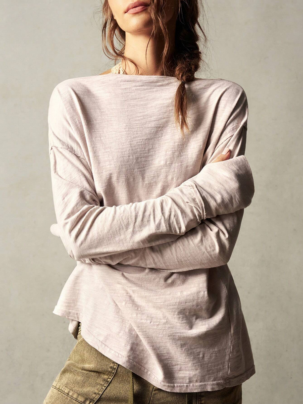 Person wearing a light pink long-sleeve top with a neutral background