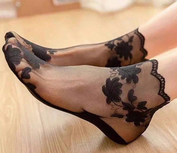 Sheer black floral socks on a light wooden floor