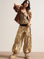 Woman wearing a brown jacket and beige pants against a plain background
