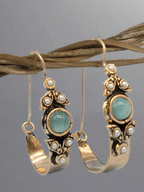 Pair of gold hoop earrings with green gemstones and pearl accents on a gray background.