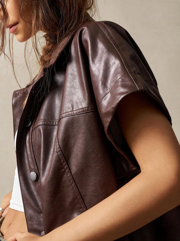 Brown leather vest worn by a person on a neutral background