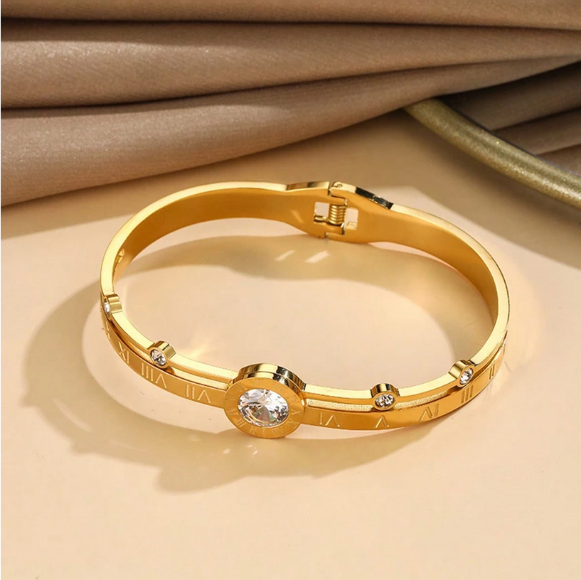 Gold bracelet with gemstones on a beige background