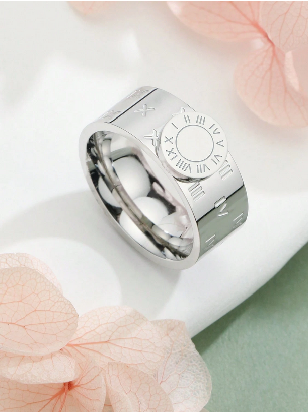Silver ring with engraved design on a white surface with pink flowers