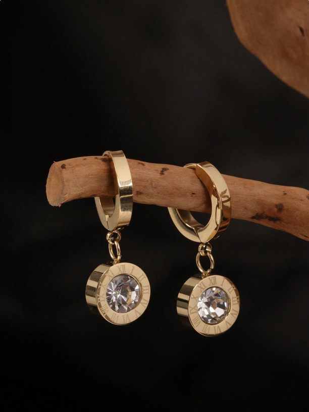 Gold hoop earrings with crystal drops on a dark background