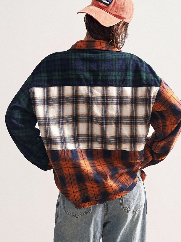 Person wearing a plaid shirt with a patchwork pattern on a plain background