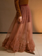 Person wearing a long, sheer pink skirt with a blurred background