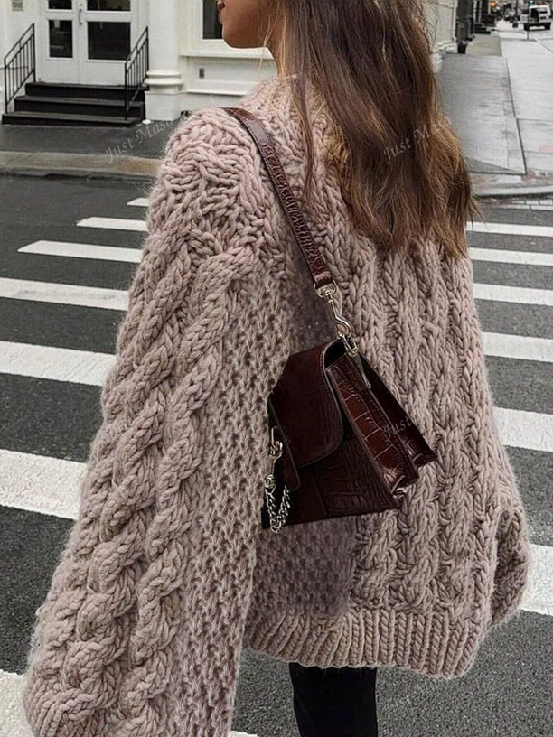 Person wearing a large knitted cardigan on a city street