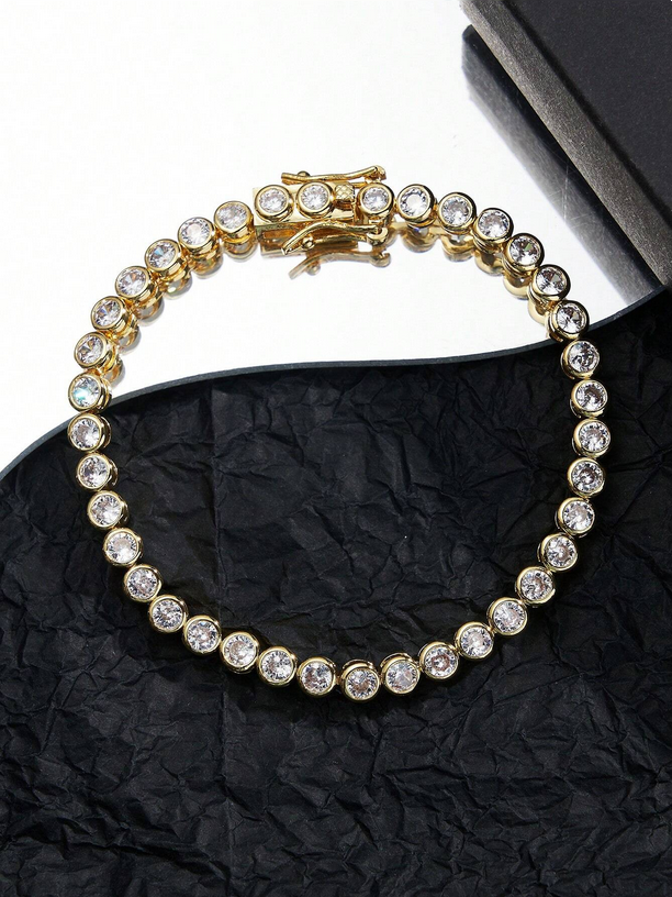 Gold bracelet with clear stones on a black textured surface
